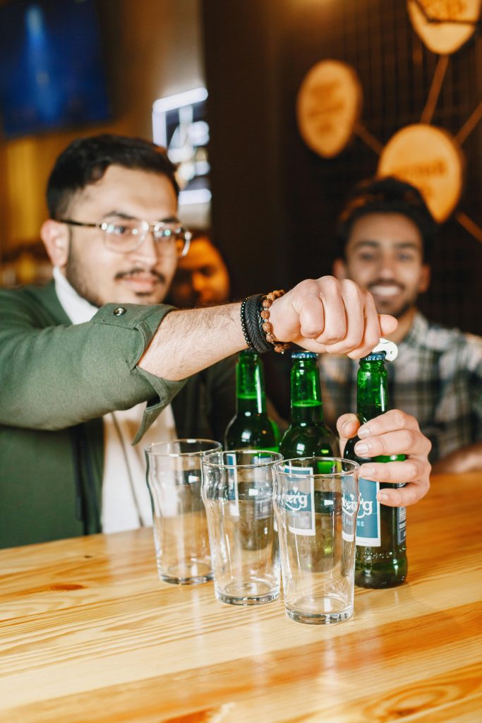 Friends opening beers at a bar counter