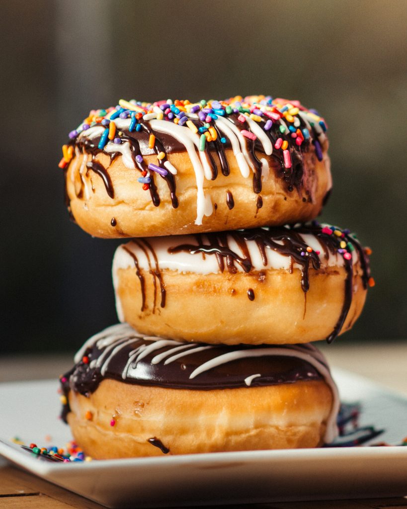 Stack of glazed donuts with chocolate drizzle and rainbow sprinkles