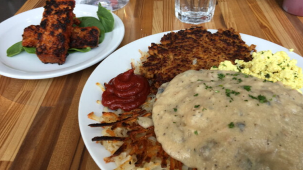 Vegan breakfast plate with hash browns, gravy, tofu scramble, and plant-based sausage